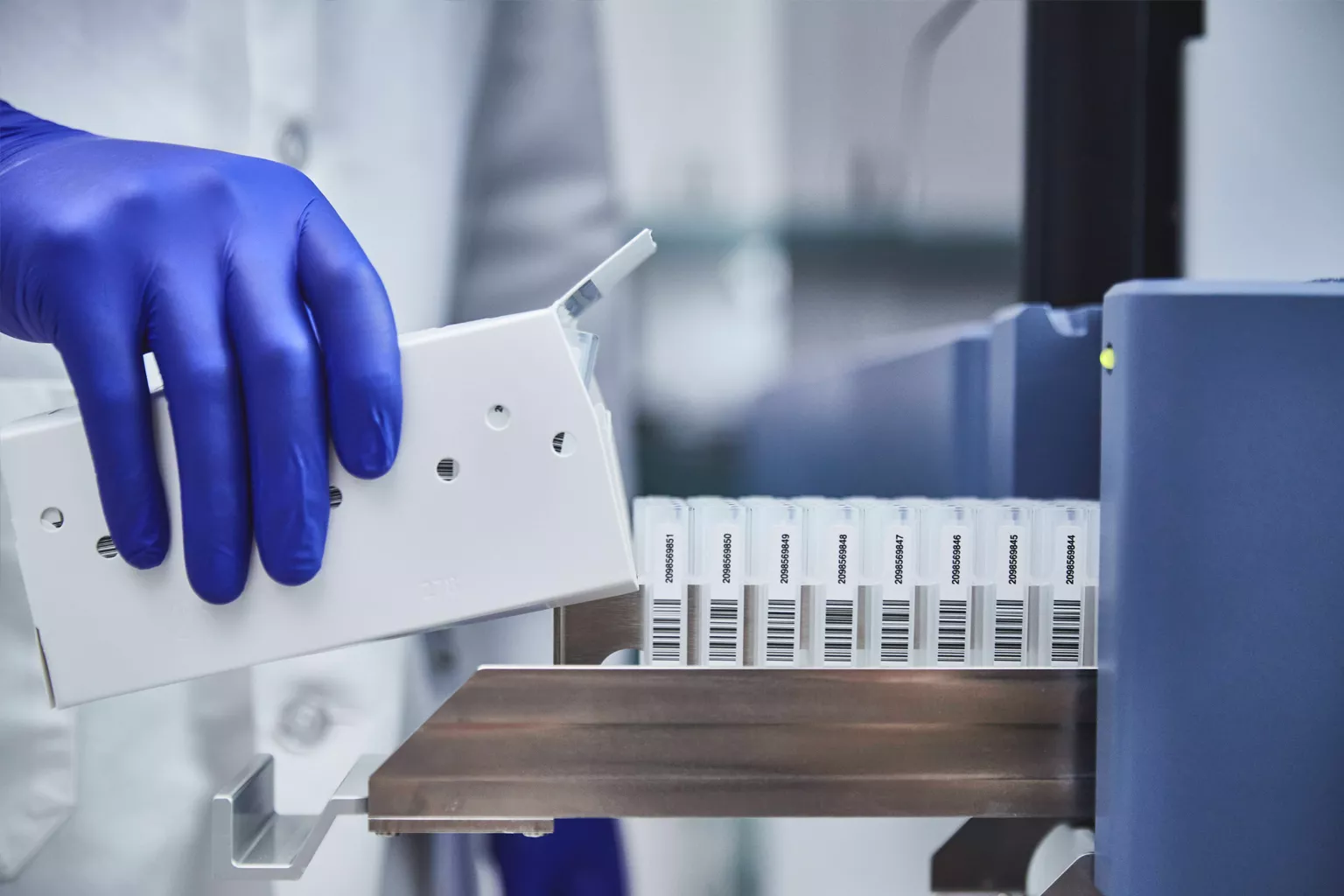 Laboratorietekniker lastar bricka med rör i laboratoriemiljö