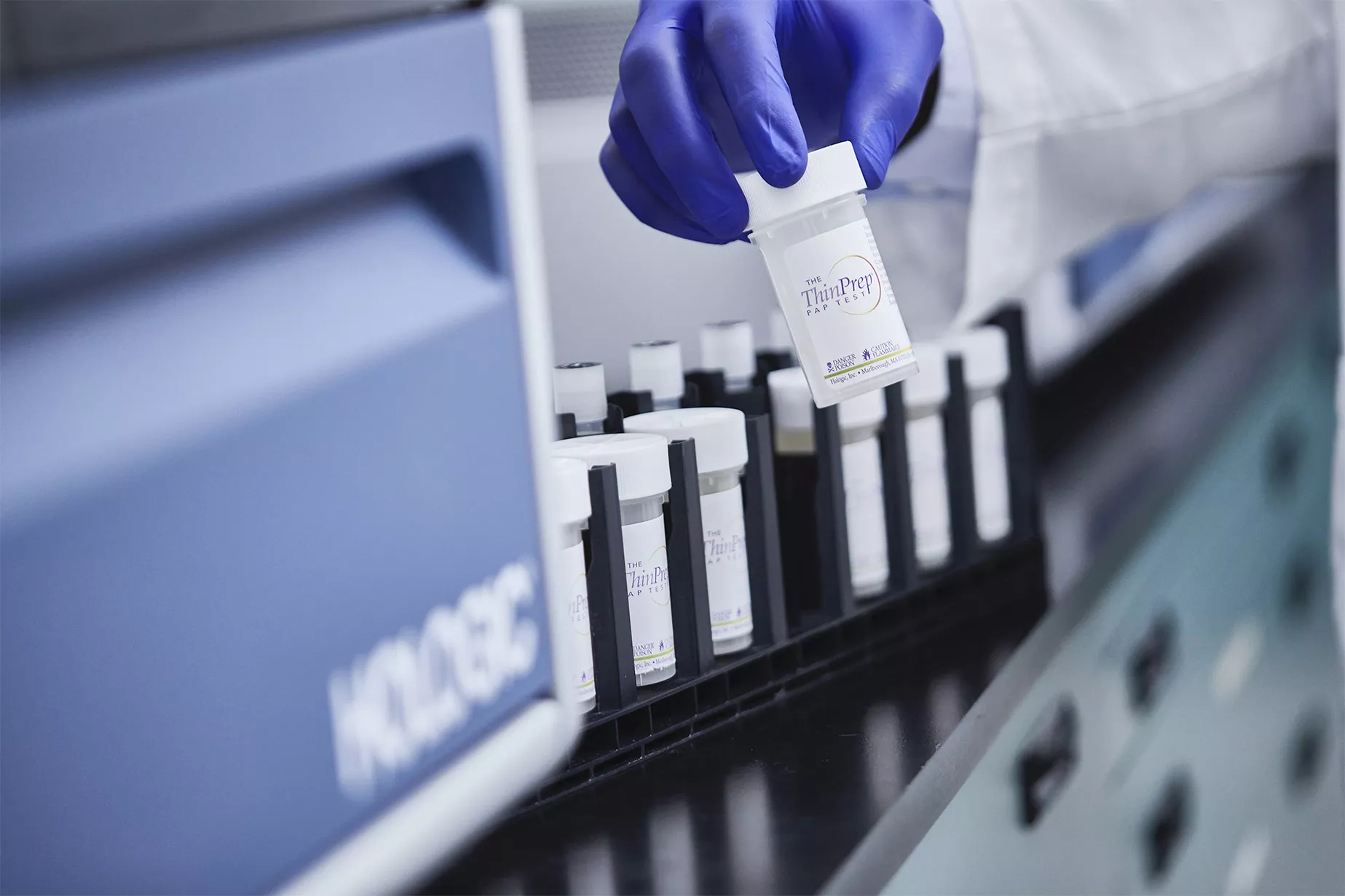 Handskbeklädd hand som håller en provtagningsburk